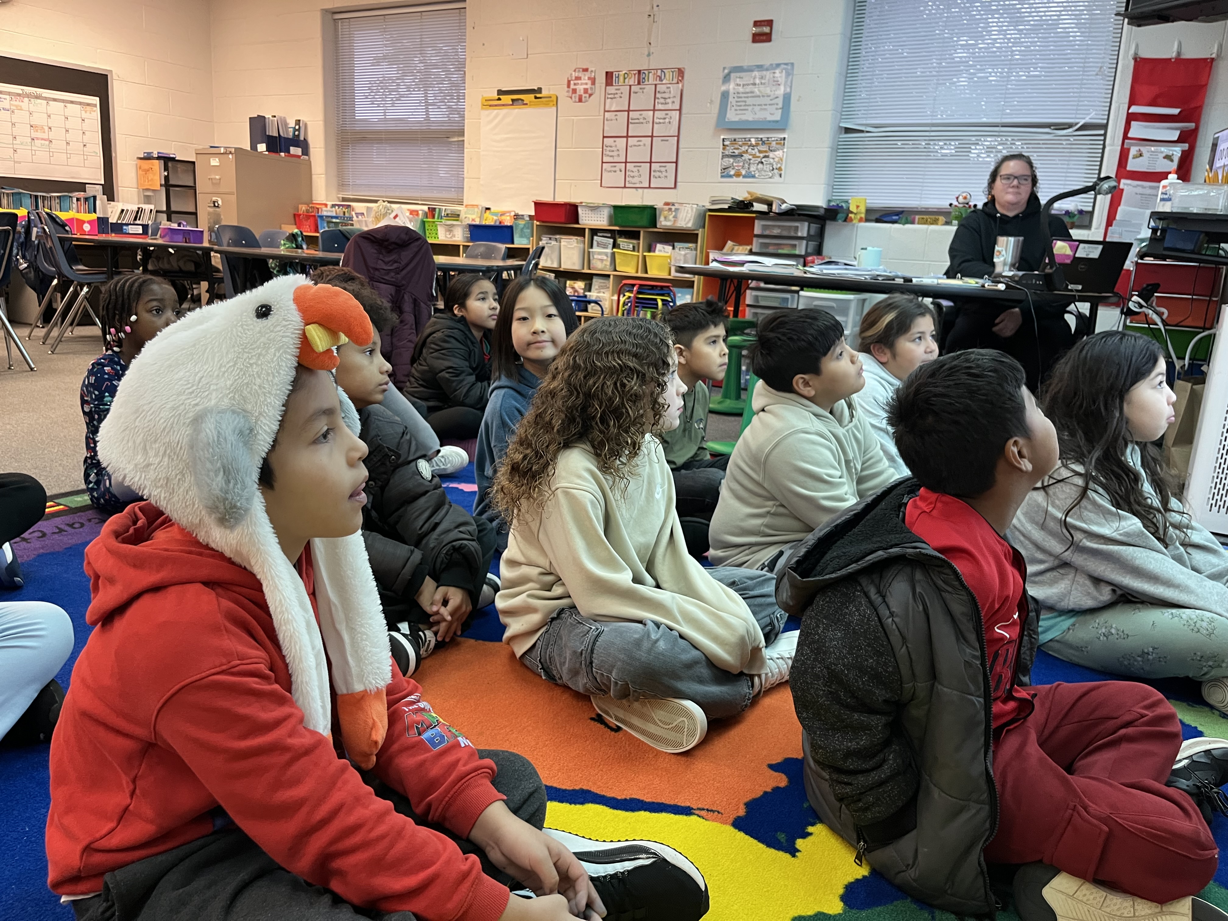 Students sitting on a carpet participating in Morning Meeting